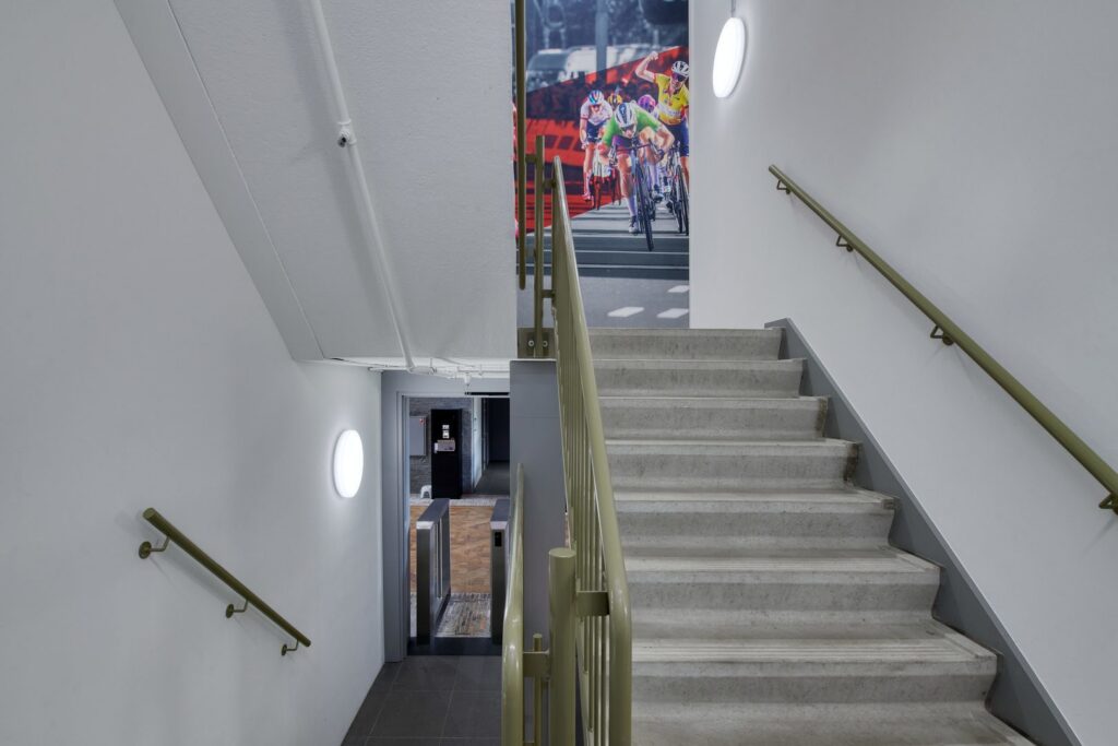 Trapphusfotografi med två moderna runda väggarmaturer som sprider jämnt, bländfritt LED‑ljus och skapar trygghet i entré och trappsteg, energieffektiva och robusta armaturer för offentliga miljöer från PROLJUS AB