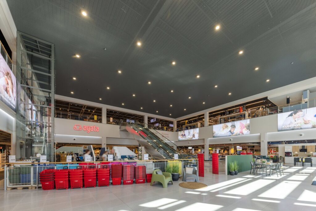 Perforerat mörkt innertak med ett rutnät av infällda LED-armaturer som ger jämn, bländfri och energieffektiv belysning i ett stort köpcentrum, idealisk för butiksytor och visuell atmosfär, levererad av PROLJUS AB