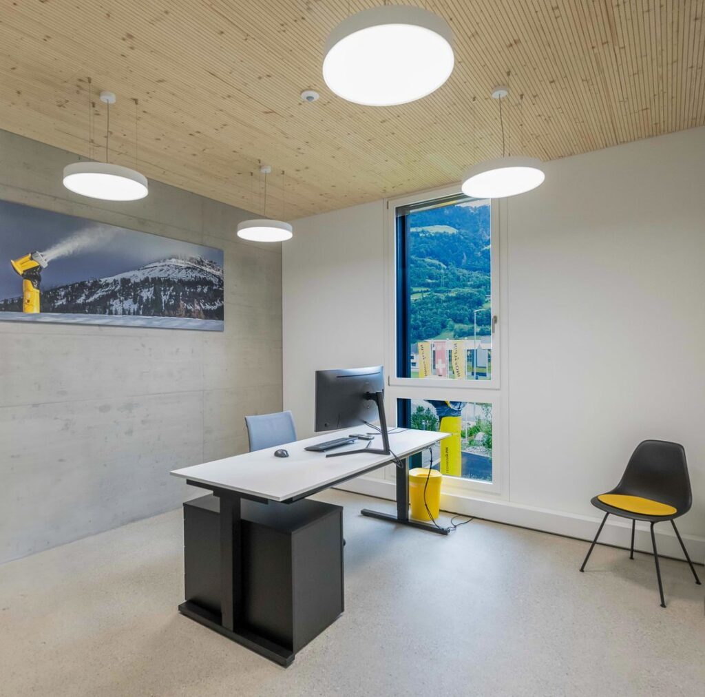 Tre runda vitlackerade takpendlar och en rund plafond från PROLJUS AB över ett modernt kontorsbord, ger energieffektivt och bländfritt LED-ljus som skapar jämn arbetsbelysning och ett stilrent professionellt intryck