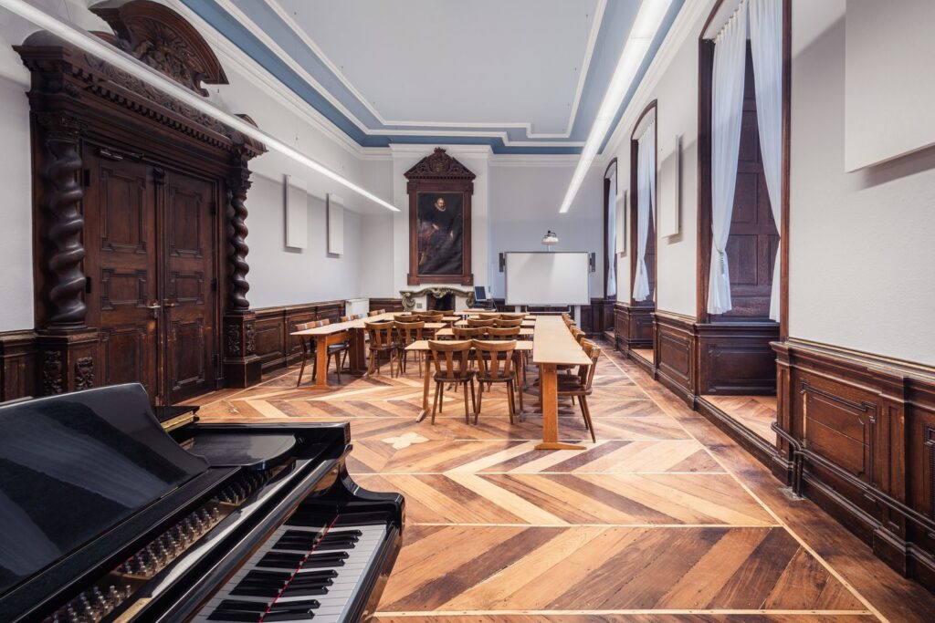 Långsträckta LED‑pendlar från PROLJUS AB i ett historiskt klassrum som ger jämn, bländfri och energieffektiv allmänbelysning idealisk för skolor, mötesrum och kulturmiljöer