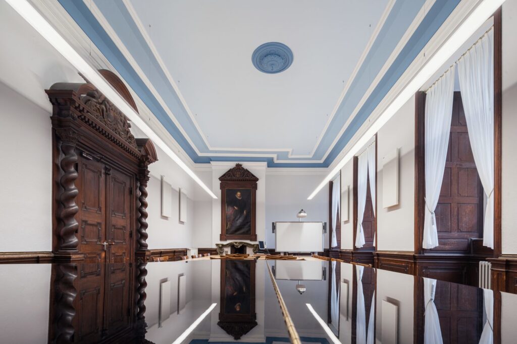 Konferensrum med två parallella linjära suspenderade armaturer från PROLJUS AB som ger jämnt, bländfritt vitt ljus som speglas i ett blankt bord och erbjuder en energieffektiv, professionell belysningslösning för kontor och mötesrum från PROLJUS AB