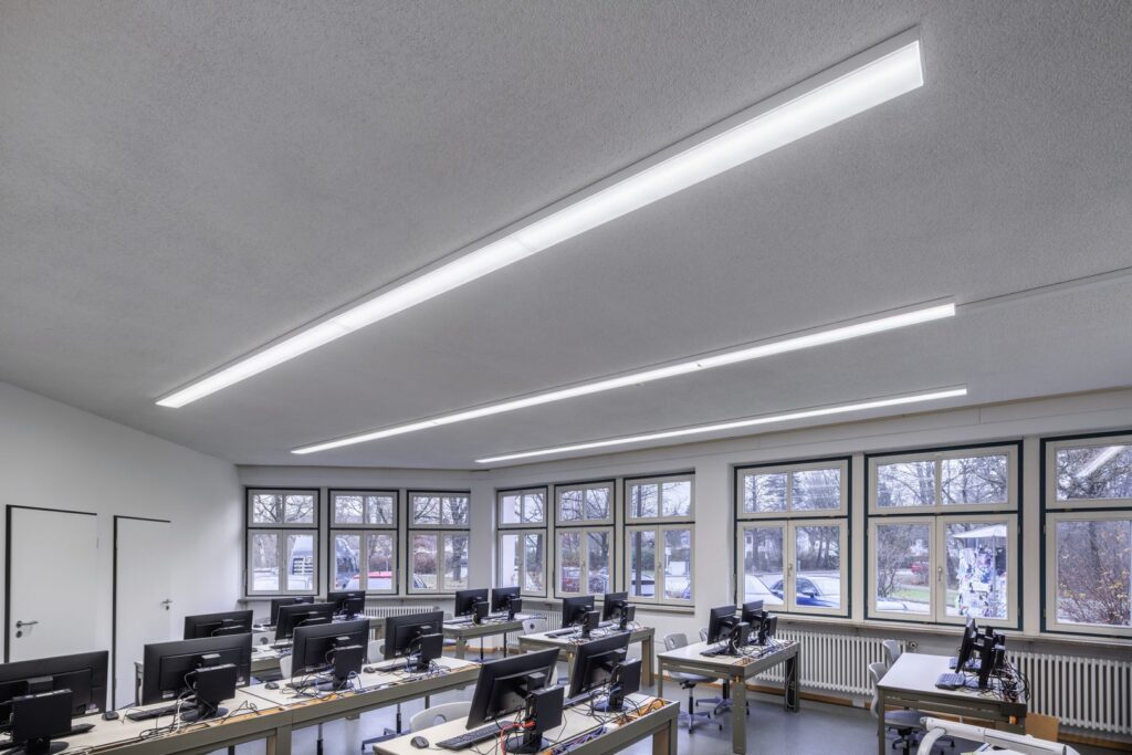 Långa infällda linjära PROLJUS AB LED-armaturer i taket över ett datorklassrum som skapar jämnt, bländfritt och energieffektivt arbetsljus över rader av skärmar och framhäver armaturernas moderna design, enkel installation och driftsekonomi