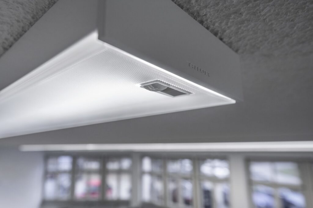 Slimmat takarmatur från PROLJUS AB i vitt med diffus prismeleffekt och diskret sensormodul, ger jämnt, energieffektivt arbetsljus som förbättrar kontorsmiljö och minskar driftkostnaderna