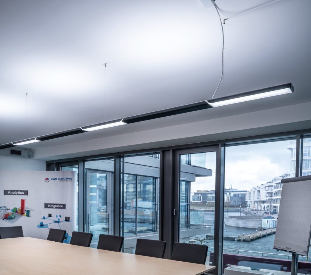 Hängande linjärarmatur från PROLJUS AB som ger jämnt, energieffektivt ljus över ett konferensbord i modern kontorsmiljö och signalerar stilren, högkvalitativ design