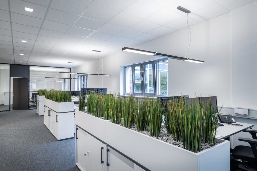 Elegant kontorslandskap upplyst av PROLJUS ABs linjära hängarmaturer med bländfritt LED-ljus som ger jämn belysning, energieffektivitet och skandinaviskt minimalistisk design för professionella arbetsplatser