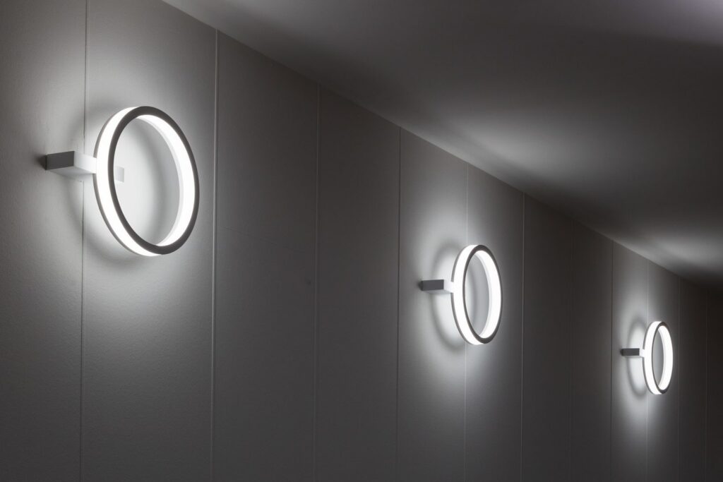Modern cirkulär väggarmatur från PROLJUS AB monterad i rad på ljusgrå vägg, energieffektiva LED-ringar som ger jämnt mjukt ljus och en minimalistisk design som förhöjer hotell, kontor och offentliga miljöer