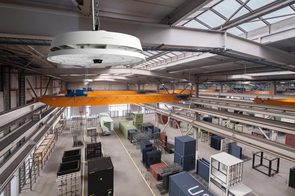 Stor cirkulär PROLJUS AB industrilampa hängande i taket i en ljus lagerhall med traverskranar, visar robust konstruktion, stark och jämn LED-belysning och energieffektivitet idealisk för fabrik, lager och logistik, kontakta PROLJUS AB för offert