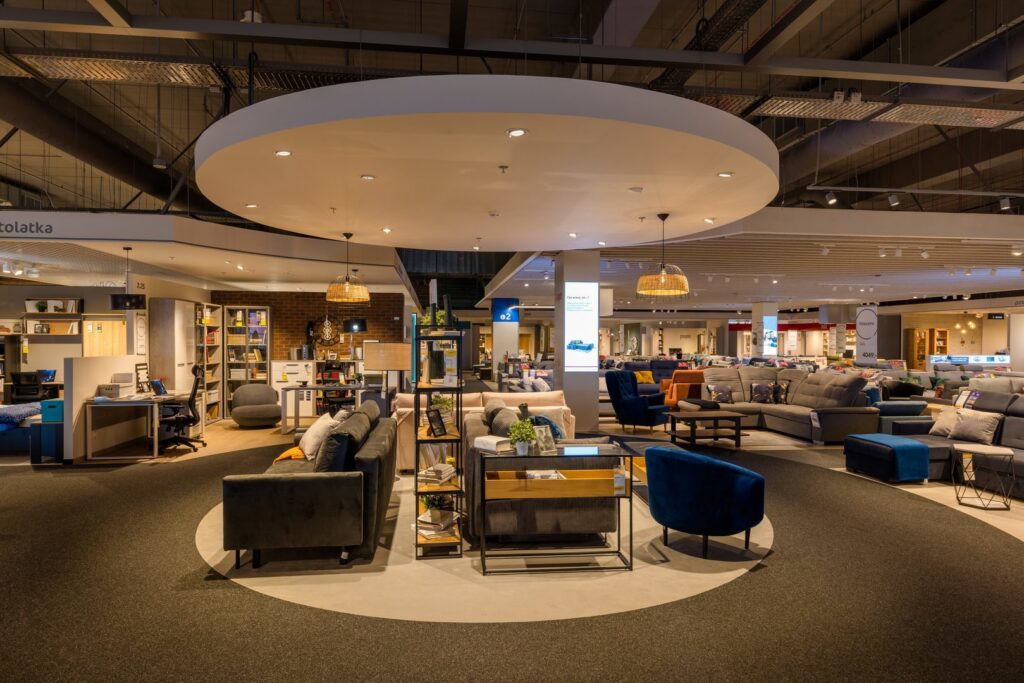 Välbelyst möbelshowroom där PROLJUS AB:s infällda spotlights i en stor rund takportal och varma rottingpendlar ger fokuserat och stämningsfullt ljus som framhäver möblernas färger och texturer, perfekt för butiksmiljöer och heminredning från PROLJUS AB