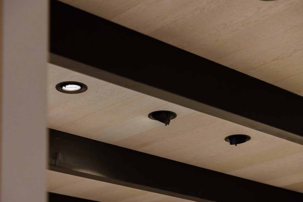 Takpanel i ljust trä med infällda spotlights och svarta armaturer som visar PROLJUS ABs kvalitetsbelysning och elegant design