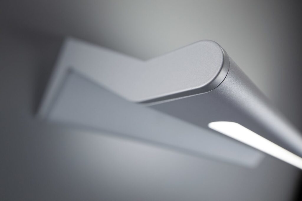 Close-up av en stilren borstad aluminiumarmatur med mjukt avbländat LED-ljus, modern design och hög ljuskvalitet från PROLJUS AB perfekt för kontor och offentliga miljöer