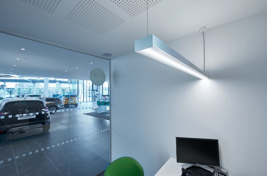 Hängande linjär LED-armatur från PROLJUS AB i modern bilhallsmiljö med jämnt, bländfritt ljus, slimmat aluminiumhus och energieffektiv teknik som lyfter arbetsmiljö och visar produkter i bästa ljus