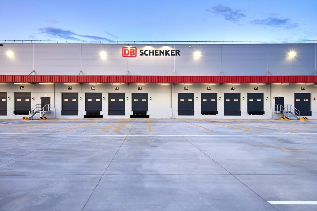 Distributionscenter i skymning upplyst av PROLJUS ABs kraftfulla och energieffektiva LED-armaturer som ger jämn, bländfri belysning över lastkajer och förbättrar säkerhet och produktivitet i logistikanläggningar