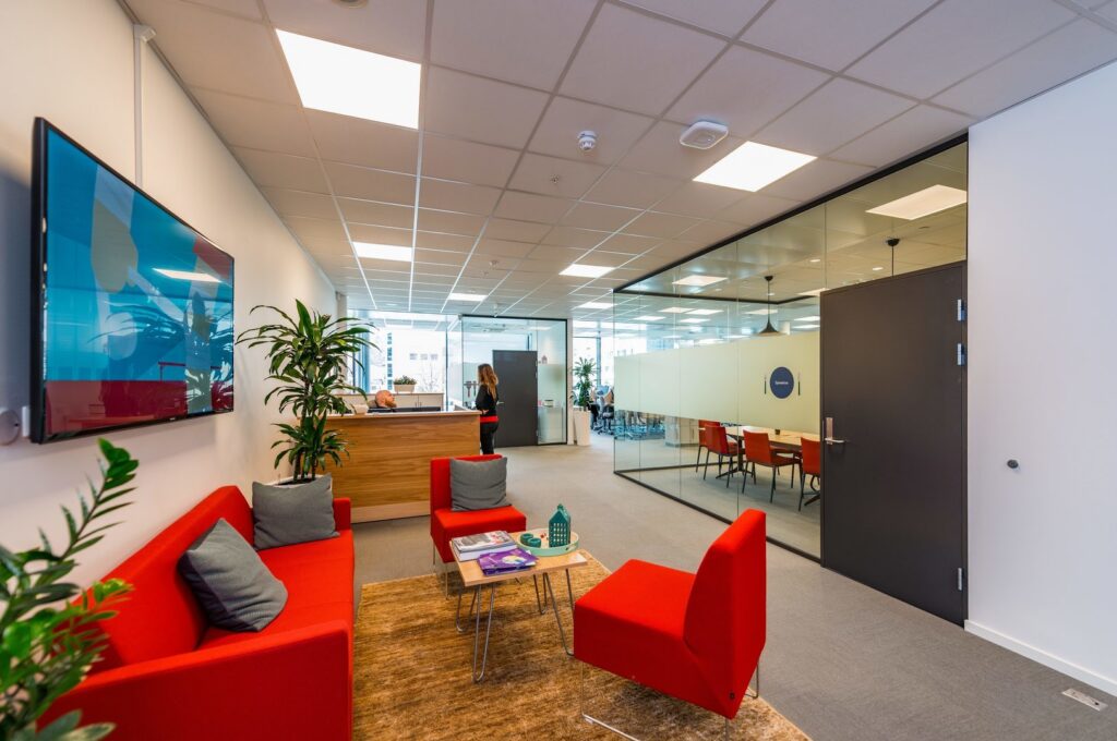 Kontorsentré belyst av jämnt fördelade infällda LED-paneler i undertaket som skapar bländfri, energieffektiv och inbjudande ljusmiljö över reception och mötesrum, en idealisk lösning från PROLJUS AB