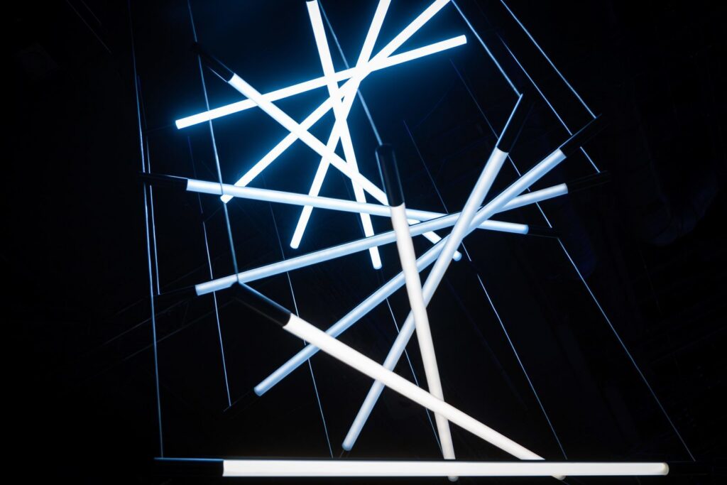 Skapande ljusinstallation med korsande LED-rör i kallt blåvitt sken som visar PROLJUS ABs eleganta, energieffektiva armaturer idealiska för moderna kontor, hotell och offentliga miljöer