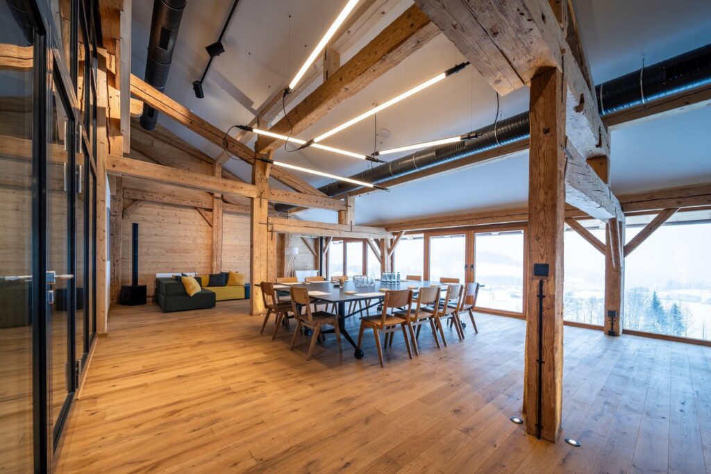 Linjära LED-armaturer från PROLJUS AB hängande i korsande geometriska linjer över ett mötesbord, ger klart och jämnt ljus som framhäver den varma träinredningen och visar PROLJUS ABs moderna och energieffektiva belysningslösningar