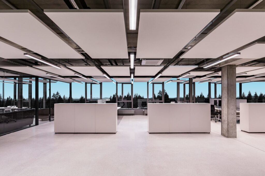 Öppet kontorslandskap med PROLJUS slimmade linjära LED-armaturer integrerade mellan akustiska takpaneler, ger bländfri, jämn och energieffektiv arbetsbelysning som ökar produktiviteten och lyfter modern estetik