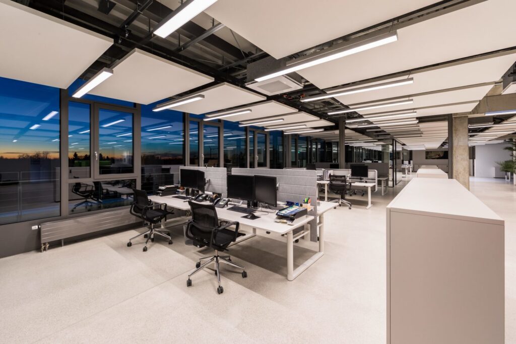 Öppet modernt kontor upplyst av PROLJUS AB:s slimmade, energieffektiva LED-armaturer integrerade mellan akustiska takpaneler för jämnt, bländfritt arbetsljus och tidlös linjär design som förbättrar funktion och estetik