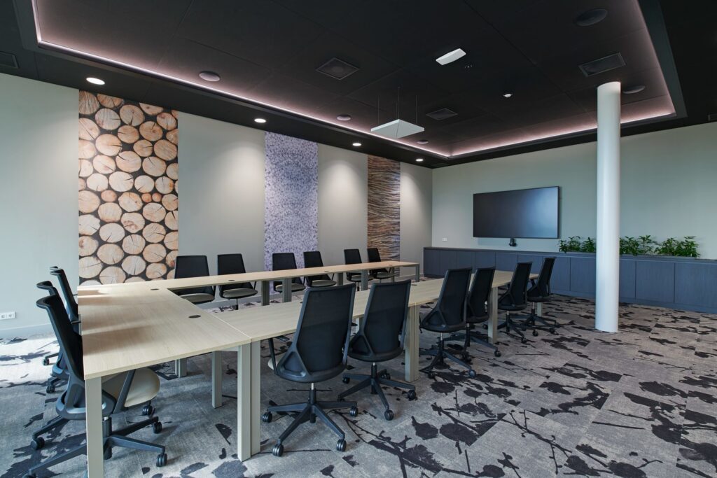 Mötesrum belyst av PROLJUS ABs armaturer med infällda rundade downlights, diskret LED-skena i taklistens innersarg och rektangulär pendel över bordet som skapar jämn, bländfri och energieffektiv arbetsbelysning som framhäver material, perfekt för moderna kontor
