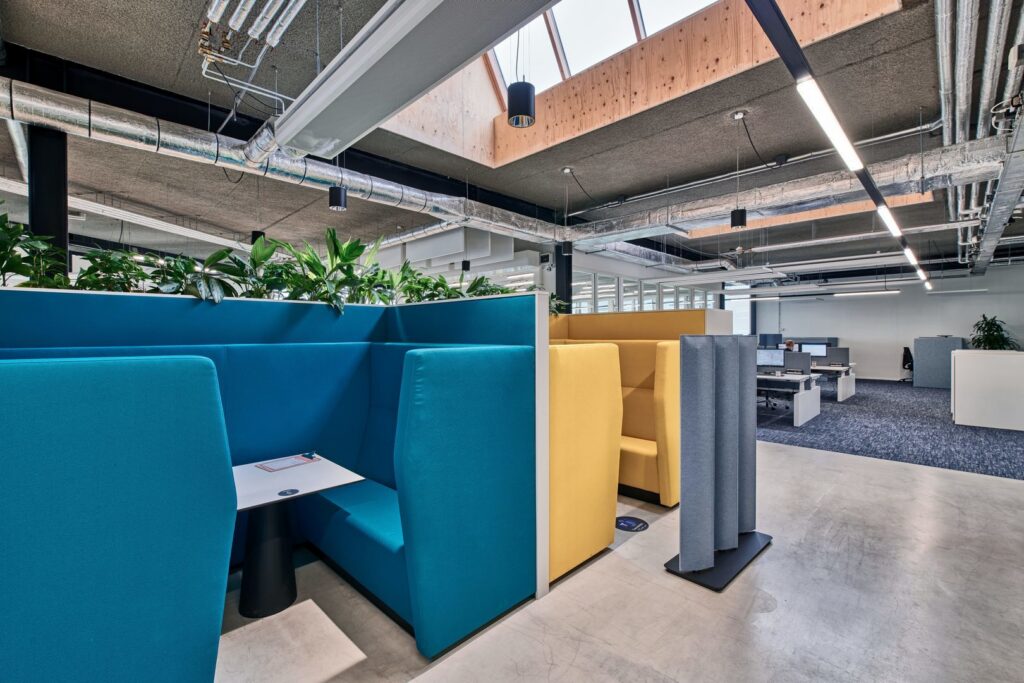 Modern kontorsmiljö upplyst av PROLJUS AB:s svarta cylindriska pendellampor och slanka linjära LED-armaturer i öppet industriloft tillsammans med naturligt dagsljus från takfönster energieffektiva och skräddarsydda belysningslösningar som höjer produktiviteten