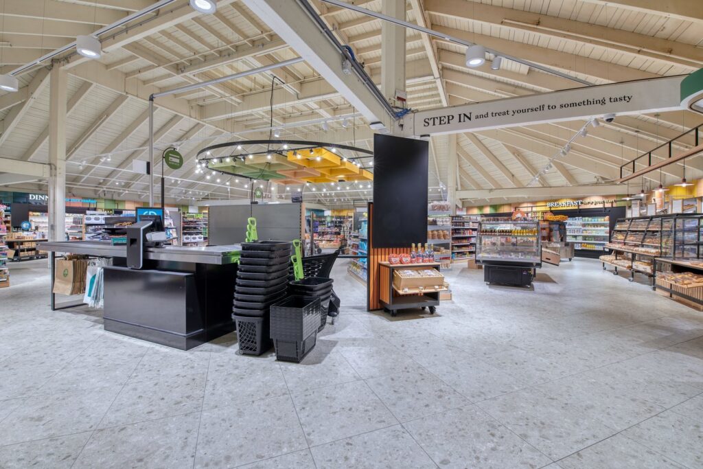 Modern livsmedelsbutik där PROLJUS AB:s LED-armaturer lyser upp ytan med en hängande ljusring med spotlights, riktade skenspottar och infällda taklampor som skapar jämn, varmvit och energieffektiv belysning perfekt för butiksmiljöer