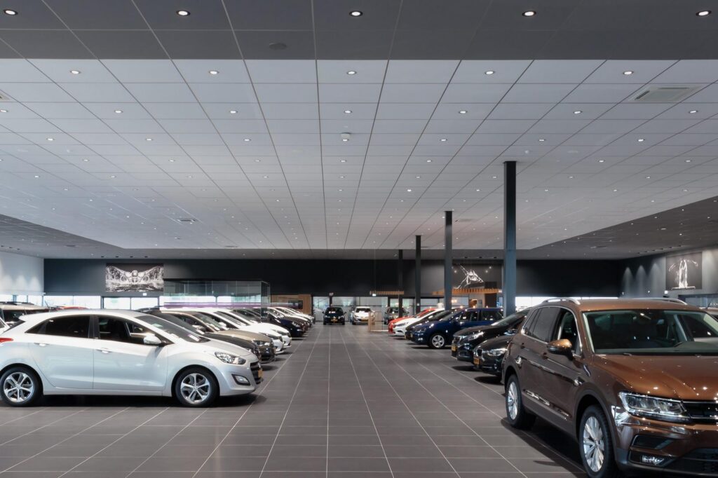Bilshowroom med ett stort rutnät av infällda energieffektiva LEDluminärer i taket som ger jämnt, bländfritt ljus och framhäver bilarnas lack och detaljer från PROLJUS AB