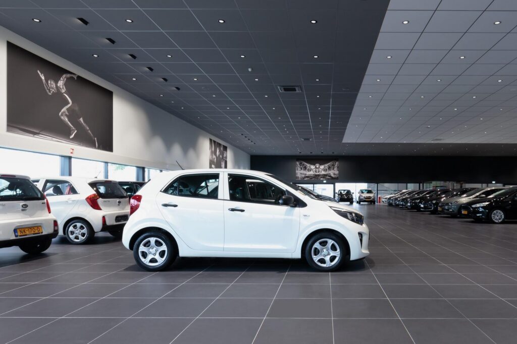 Stor bilhall upplyst av ett rutmönster av infällda LED-downlights och riktade spotlights som ger jämn, energieffektiv och säljdrivande belysning som framhäver bilarna, en modern belysningslösning från PROLJUS AB